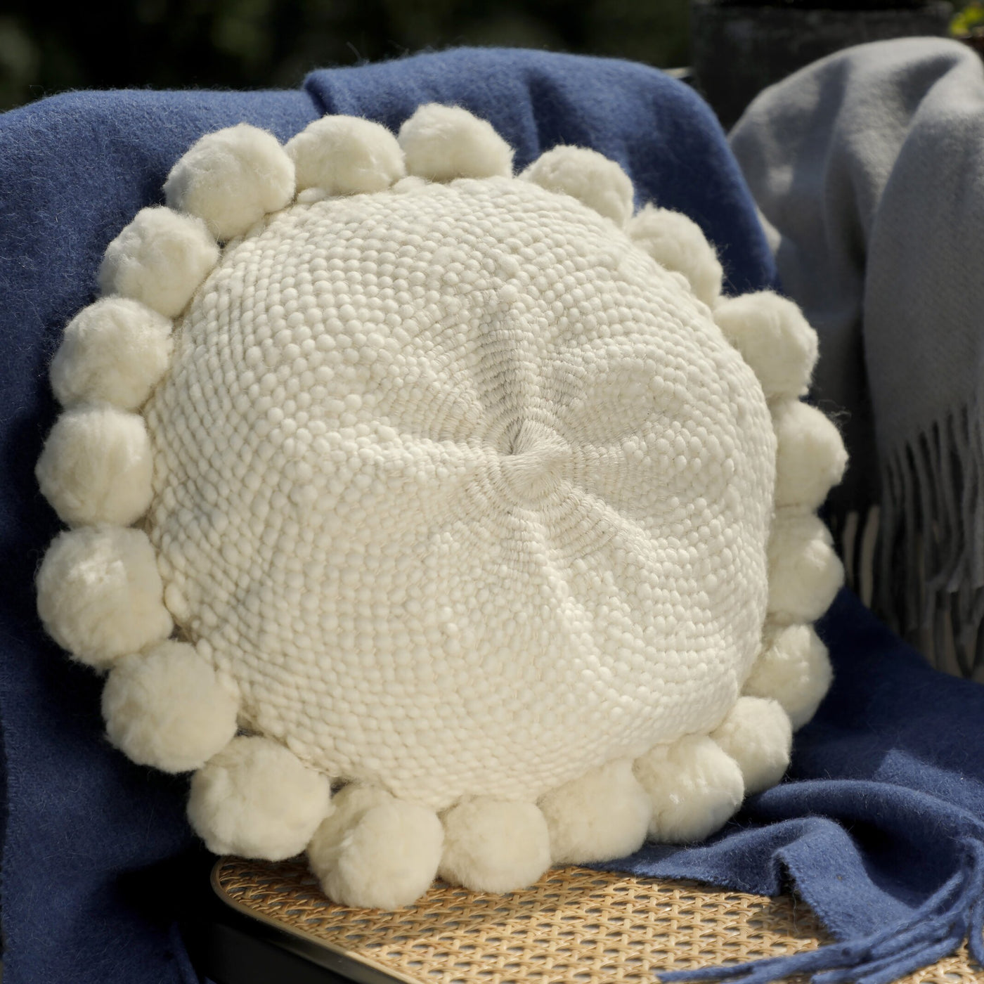 Cojín redondo de lana de oveja con pompones